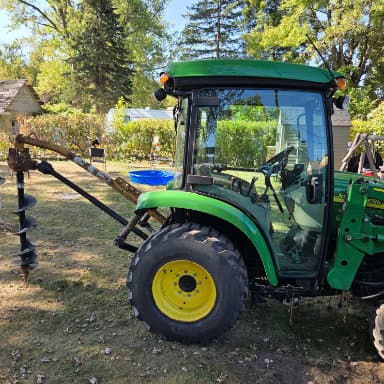 Side picture of a green tractor with driller